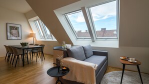 A modern loft apartment with a dining area, a sofa, and a small table with a cup and saucer. - Vienna Residence, Prater - Exhibition Center #6485 (Vienna)