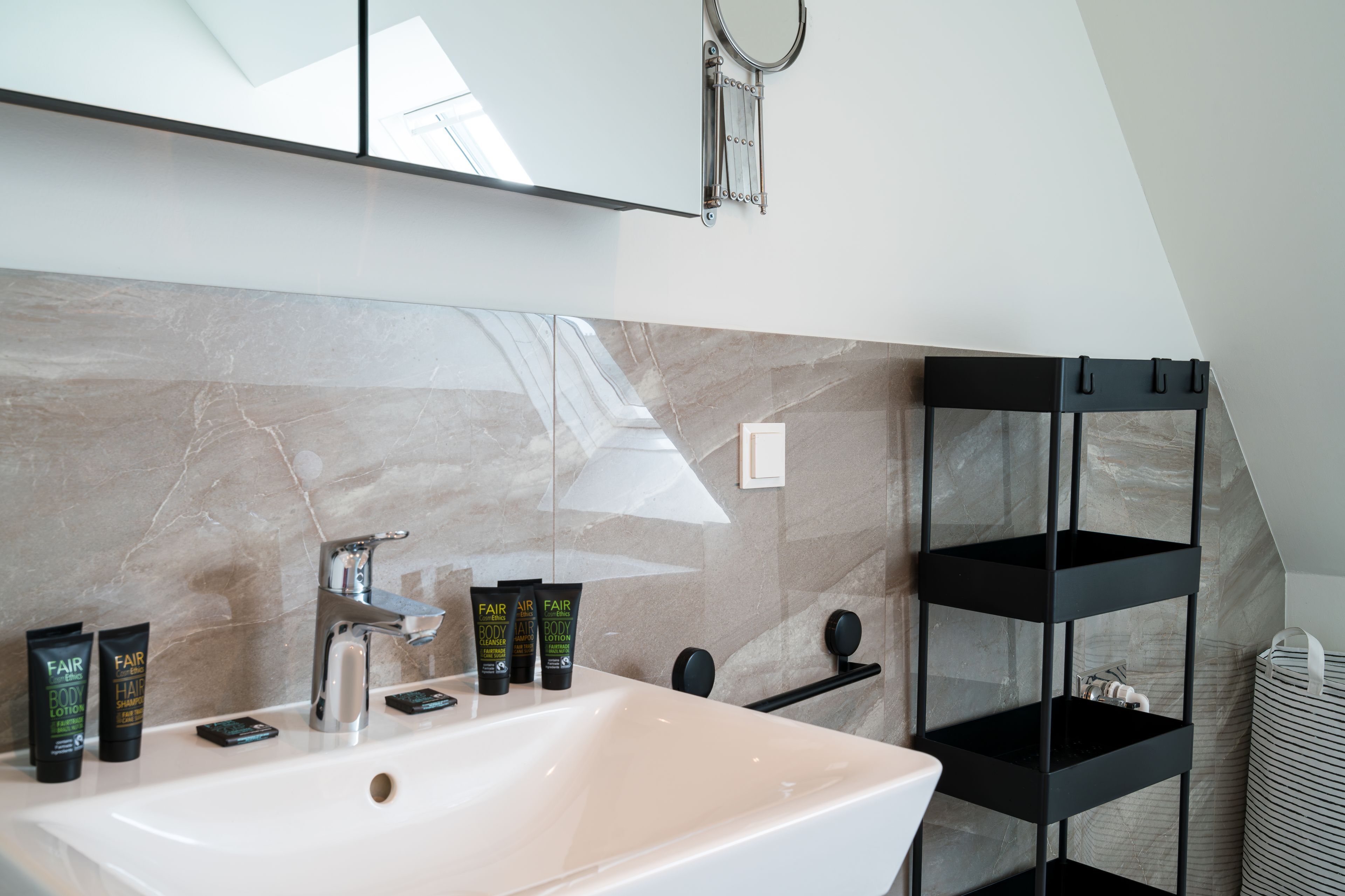 A bathroom with a large sink, mirror, and shelves.
