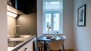Et kompakt køkken med vask, komfur og spiseplads med stole og bord.