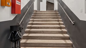 A staircase with a handrail, a fire alarm, and a first aid kit on the wall. - Vienna Residence, Prater - Exhibition Center #6460 (Vienna)