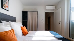 A hotel room with a bed, pillows, a headboard, a window, and an air conditioning unit. - Vienna Residence, Prater - Exhibition Center #6460 (Vienna)