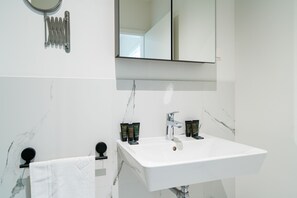 A modern bathroom with a white sink, two mirrors, and toiletries on the counter. - Vienna Residence, Prater - Exhibition Center #6460 (Vienna)