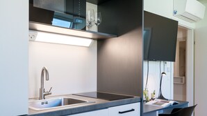A modern kitchen with a built-in sink, a countertop, and a small dining area with a chair and a table. - Vienna Residence, Prater - Exhibition Center #6482 (Vienna)