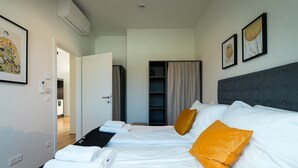 Une chambre d’hôtel comprenant un lit, deux oreillers, une armoire et une porte donnant sur une autre pièce.