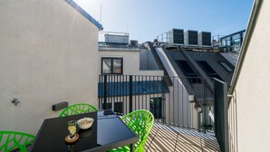 Une terrasse sur le toit avec une table et des chaises, une vue sur le ciel et des unités de climatisation.