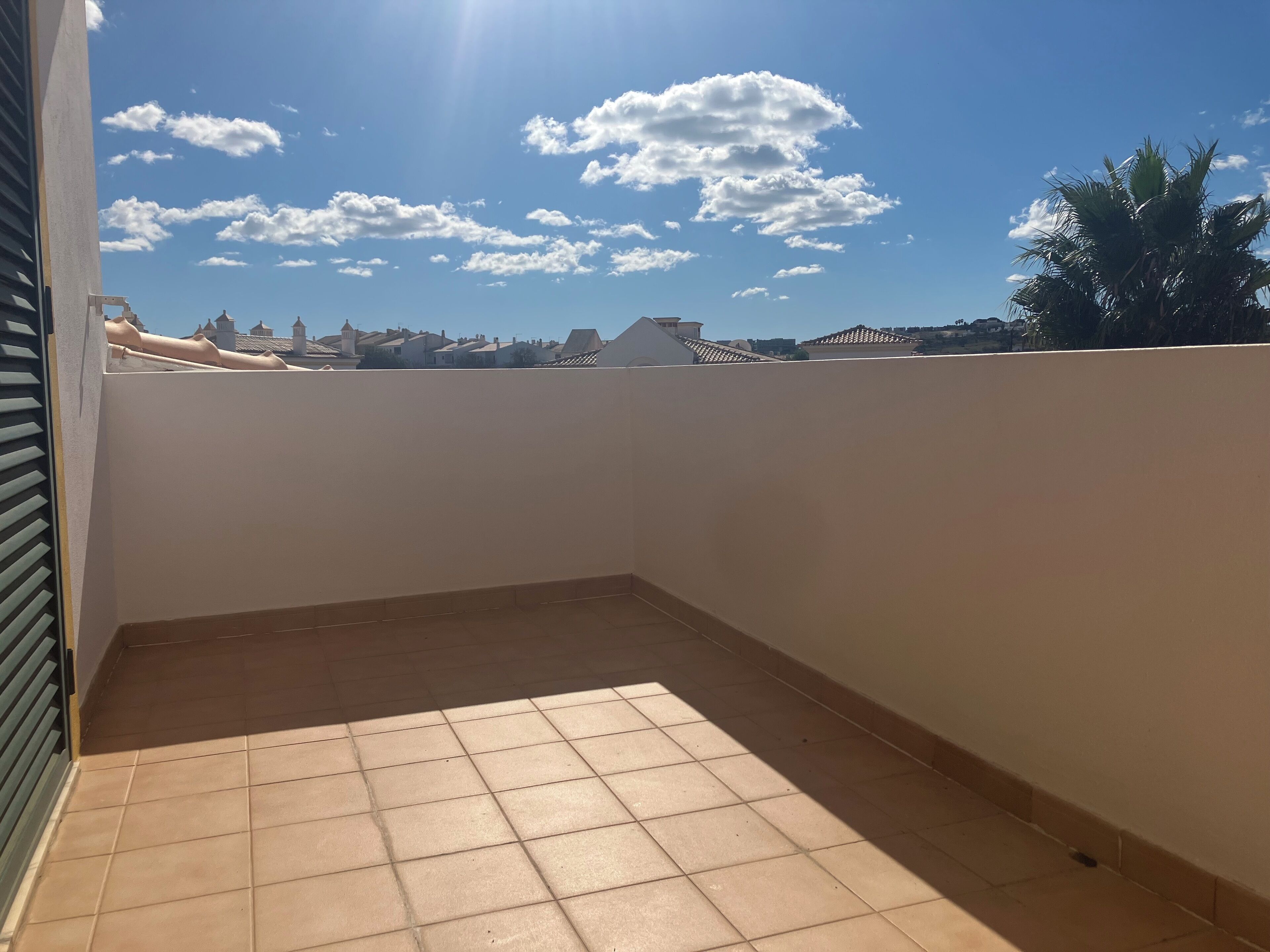 Une terrasse sur le toit, dotée d’un sol carrelé et d’un mur blanc.