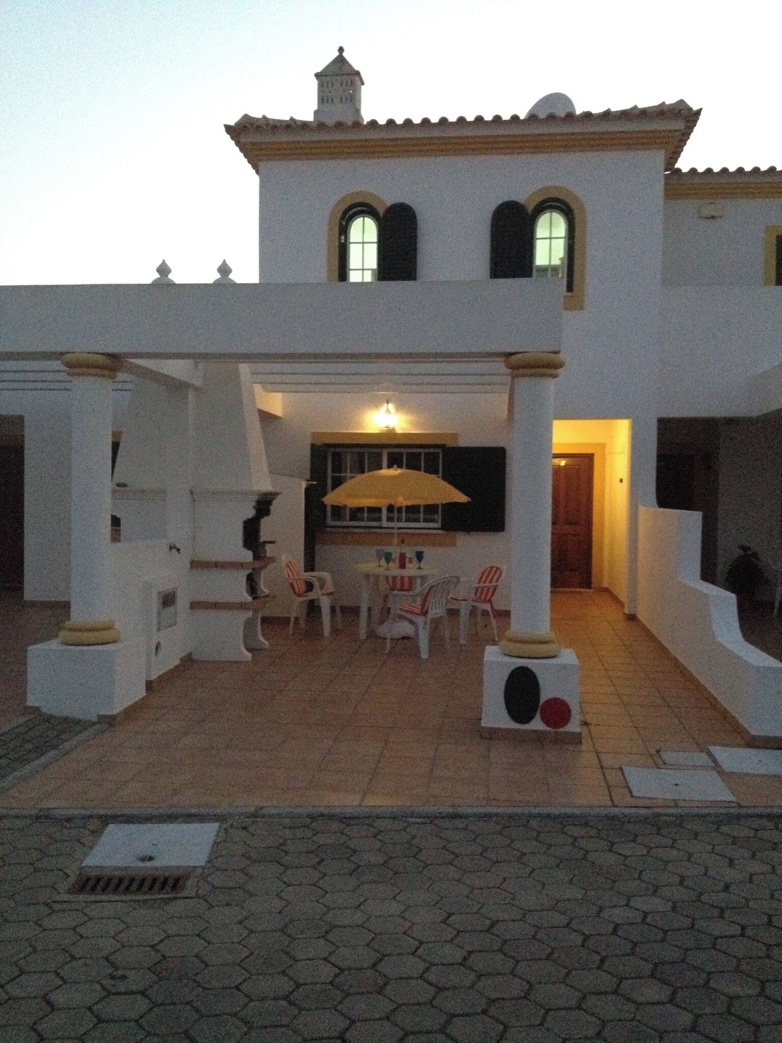 Un bâtiment à deux étages doté d’un patio comprenant une table et des chaises, un espace salon couvert et une petite piscine.