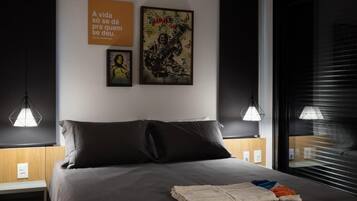 Un dormitorio moderno con una cama grande, dos lámparas colgantes y cuadros en la pared.