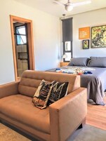 Una camera da letto moderna con un letto, un divano e una ventola a soffitto.