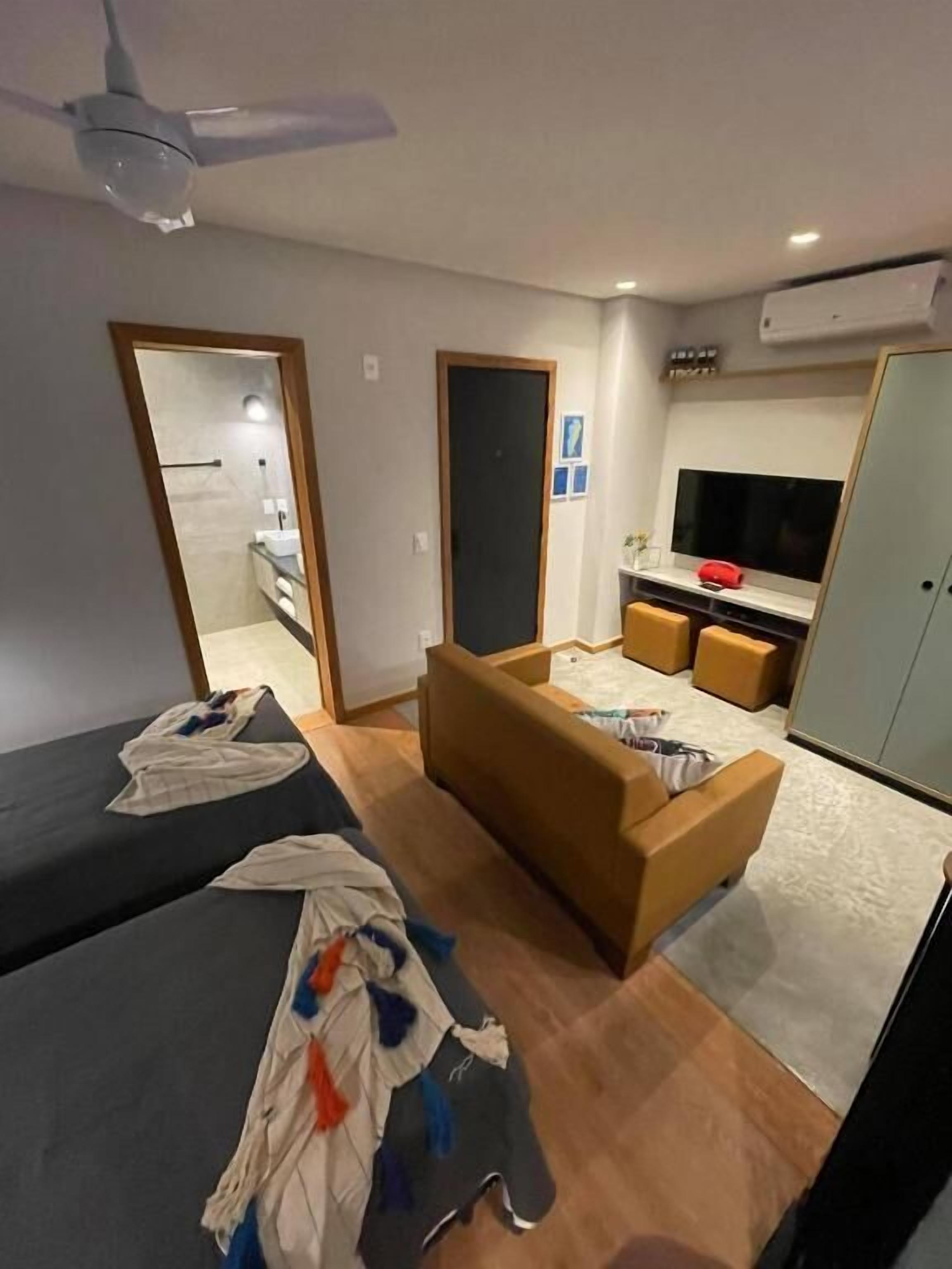 Habitación de hotel compacta con dos camas, un sofá, un televisor y un armario.