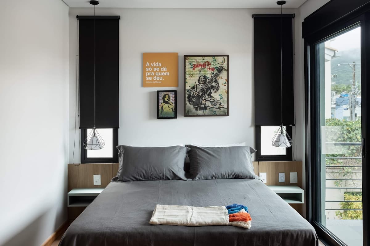 A modern bedroom with a large bed, grey bedding, and two wall art pieces.