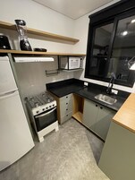 Kompakti keittiö, jossa on kaasuliesi, uuni, mikroaaltouuni ja pesuallas.
