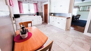 Une cuisine avec des meubles blancs, une table à manger en bois et un tapis rouge.