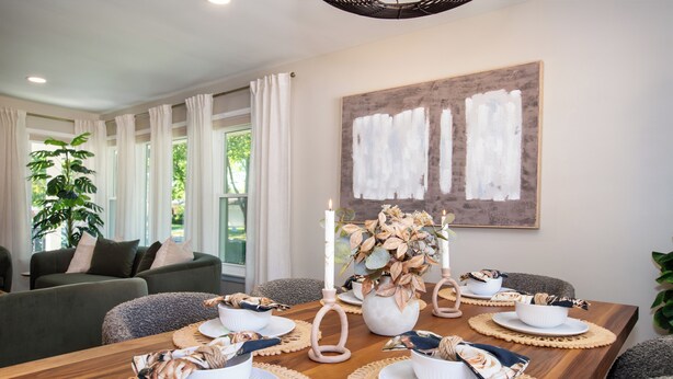 A dining area with a wooden table set for four, surrounded by grey armchairs. A large abstract painting is on the wall, and a potted plant is visible in the background. - Stylish Escape/Game Room/4 Brs (Arlington Heights)
