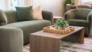 A modern living room with a green sofa, a wooden coffee table, and a wicker basket. - Stylish Escape/Game Room/4 Brs (Arlington Heights)