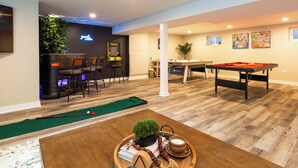 A room with a pool table, a billiards table, a green felt table, and a bar area with chairs and a neon sign. - Stylish Escape/Game Room/4 Brs (Arlington Heights)