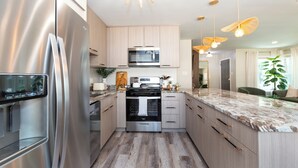 A modern kitchen with stainless steel appliances, wooden cabinets, and a marble countertop. - Stylish Escape/Game Room/4 Brs (Arlington Heights)