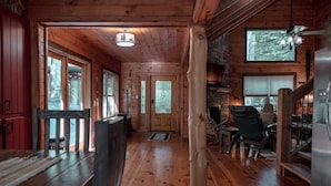 A wooden cabin interior with a dining area, a fireplace, and large windows. - Olivers Hideaway | on Fightingtown Creek (Cherry Log)