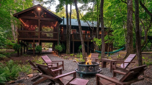 A wooden cabin with a deck and outdoor seating area, surrounded by trees. - Olivers Hideaway | on Fightingtown Creek (Cherry Log)