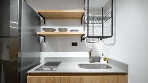 A modern kitchen with wooden cabinets, a stainless steel refrigerator, a double sink, and a dish rack. - INDIE UNIVERSE  (Medellín)