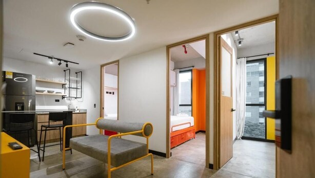 A modern, compact living space with a kitchenette, a dining area, and a bedroom. - INDIE UNIVERSE  (Medellín)