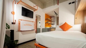 A modern hotel room with a bed, a TV mounted on the wall, and a motivational quote. - INDIE UNIVERSE  (Medellín)