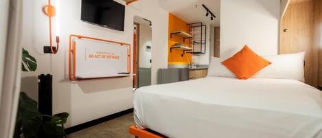 Una habitación de hotel moderna con una cama, un televisor montado en la pared y una cita motivacional.