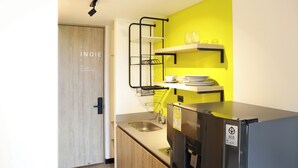 A compact kitchen with a sink, a black refrigerator, and a yellow accent wall. - INDIE UNIVERSE  (Medellín)