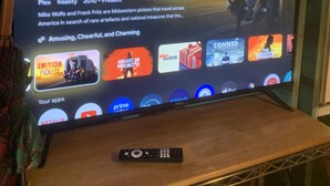 Pantalla de televisió que mostra l'espectacle 'American Pickers' amb un comandament sobre una taula de fusta.