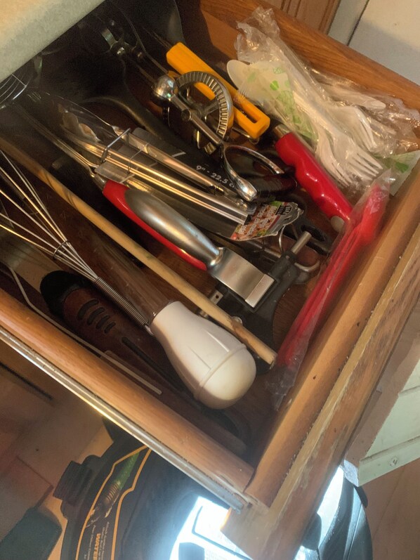 Uma gaveta com diversos utensílios e ferramentas de cozinha, incluindo batedores, um ralador e um conjunto de facas.