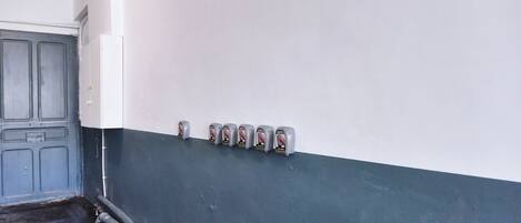 Un couloir avec une porte grise, un mur blanc et une rangée d’interrupteurs.