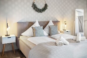 Relax in a serene space with a neatly made bed, two bedside tables, and a mirror.