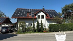 Una casa con paneles solares en el techo, un garaje y un coche estacionado al frente.