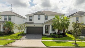 A modern two-story residential building with a garage, surrounded by well-maintained lawns and palm trees. - Stunning Home 9 Ensuites Near Disney (2615SN) (Kissimmee)