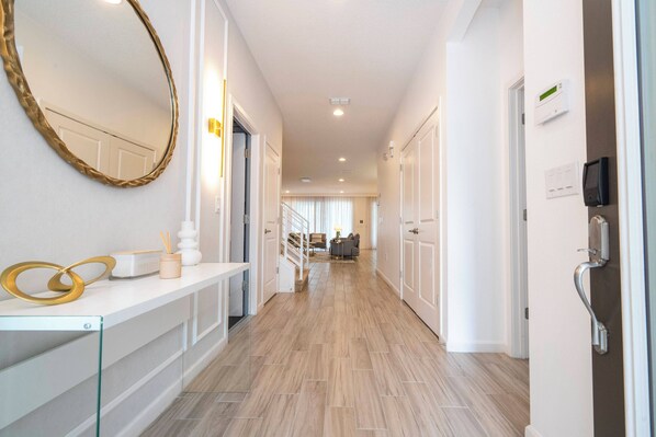 A hallway with a white reception desk, a large mirror, and a staircase leading to a living area. - Stunning Home 9 Ensuites Near Disney (2615SN) (Kissimmee)