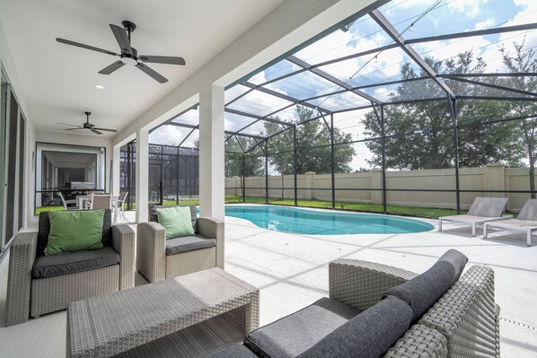 A covered outdoor area with a pool, wicker furniture, ceiling fans, and a glass enclosure. - Stunning Home 9 Ensuites Near Disney (2615SN) (Kissimmee)
