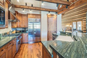 Une cuisine moderne avec des meubles en bois, des appareils en acier inoxydable et un plan de travail en marbre.