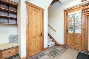 Un pasillo con puertas de madera, una escalera y un banco.