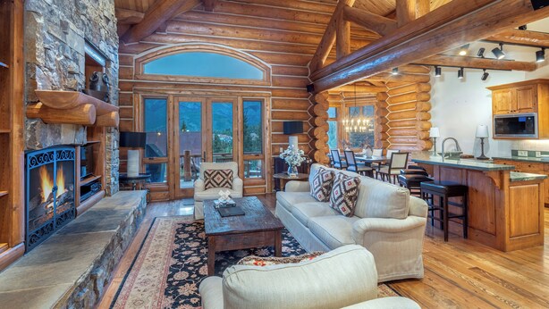 A log cabin interior with a fireplace, wooden furniture, and a stone wall. - Tristant 125- Luxury Ski-In/Out Chalet with Hot Tub (Mountain Village)