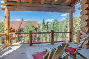 Une terrasse en bois offrant une vue sur un paysage montagneux, une chaise en bois et une balustrade en bois.