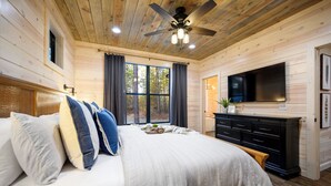 A bedroom with a bed, a ceiling fan, a TV, and a window with curtains. - NEW Listing Discounts! 1BR w/ loaded amenities! (Broken Bow)