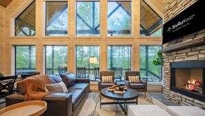 A spacious living room with a fireplace, large windows, and a stone accent wall. - NEW Listing Discounts! LUX+Amenities for everyone! (Broken Bow)
