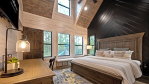 A bedroom with a large bed, wooden walls, and a sloped ceiling. - NEW Listing Discounts! LUX+Amenities for everyone! (Broken Bow)