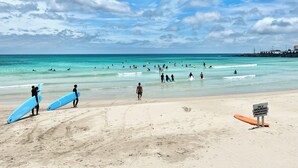 A beach with people surfing and walking along the shore.
