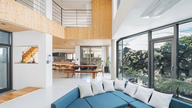 A modern interior with a blue sofa, wooden accents, and large windows offering a view of a rocky landscape.