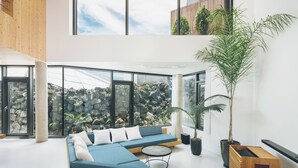 A modern living room with a blue sectional sofa, a round coffee table, and a large potted plant.