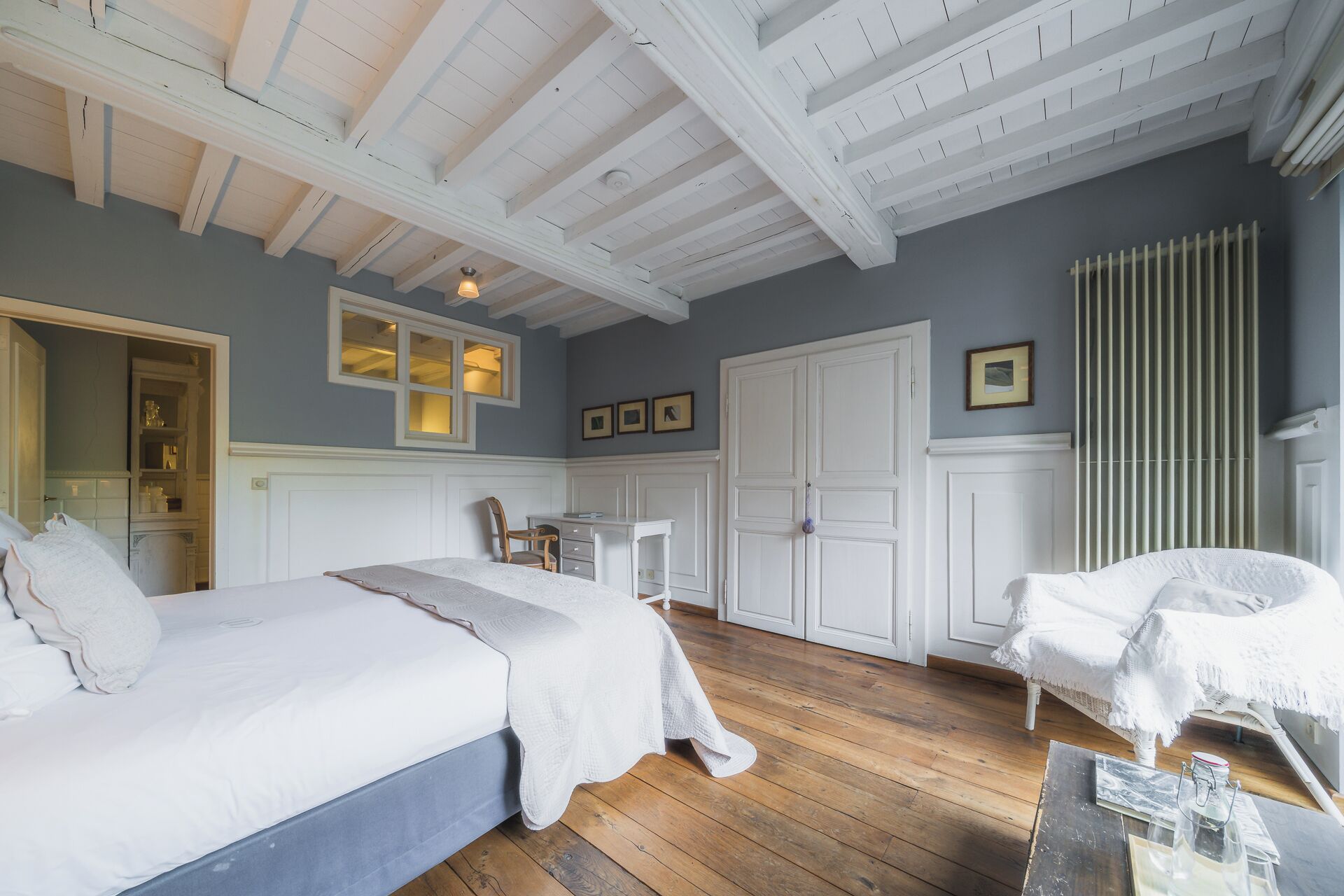 A bedroom with a large bed, a smaller bed, a chair, a desk, and a wardrobe.