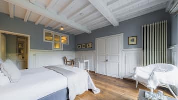 A bedroom with a large bed, a smaller bed, a chair, a desk, and a wardrobe.