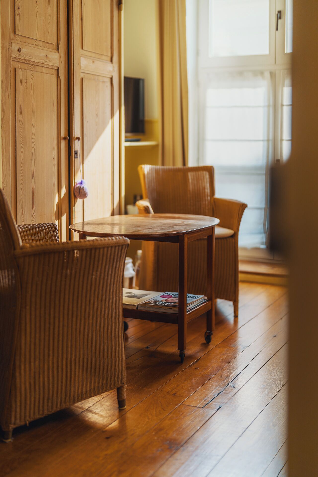 A wooden dining table with chairs, a wooden floor, and a door in the background.