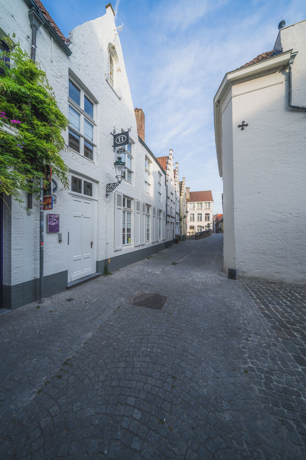 A cobblestone street lined with white buildings, some with visible doors and windows.